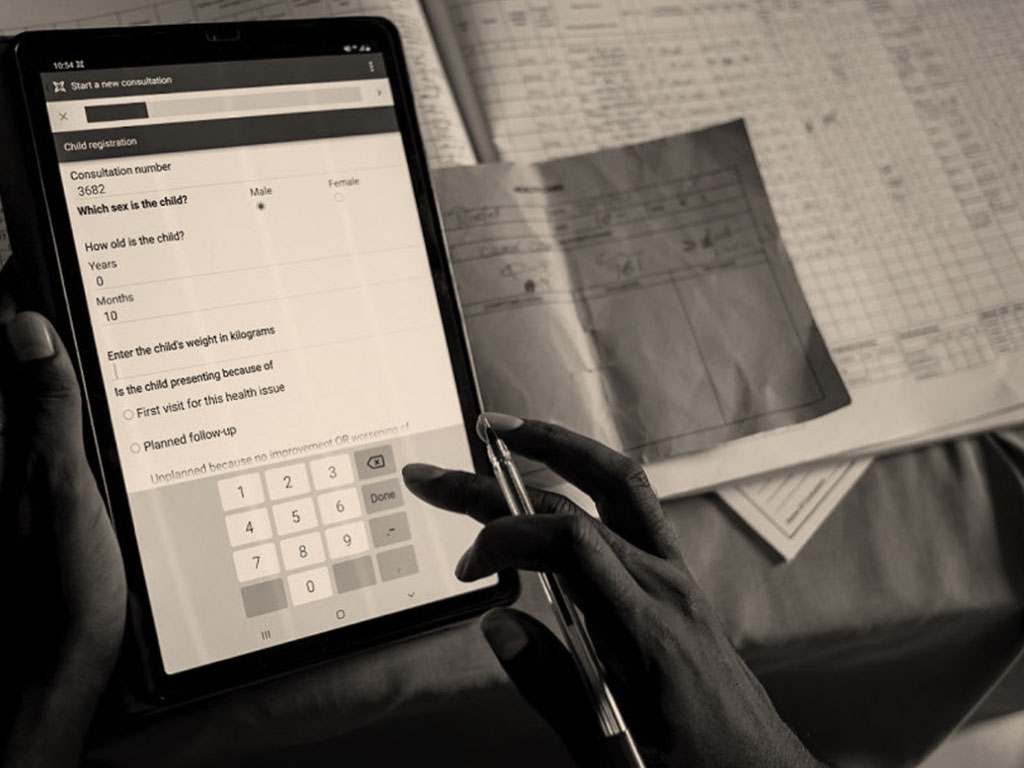 Health worker entering child registration data on a tablet, representing digital health solutions