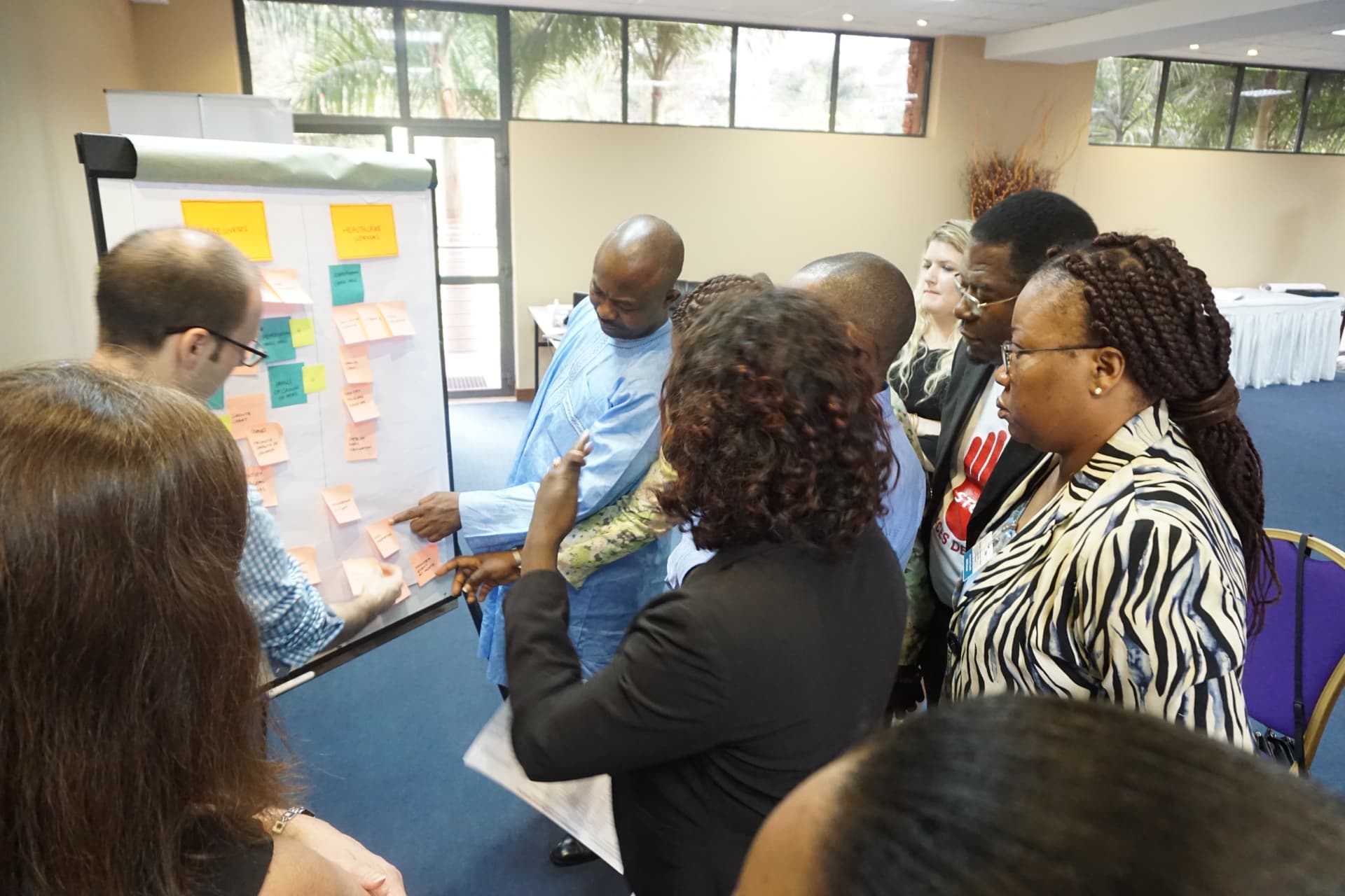 Workshop participants gathered around a flip chart covered in colourful sticky notes